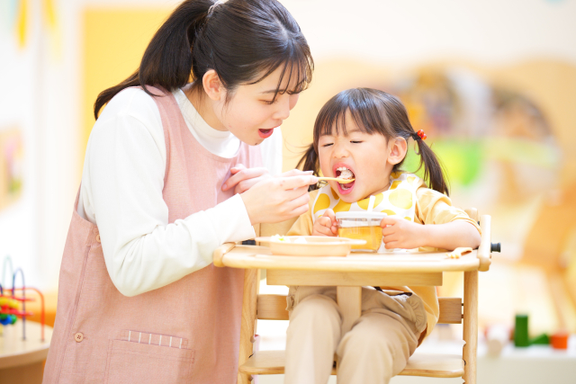 先生にご飯を食べさせてもらっている女の子