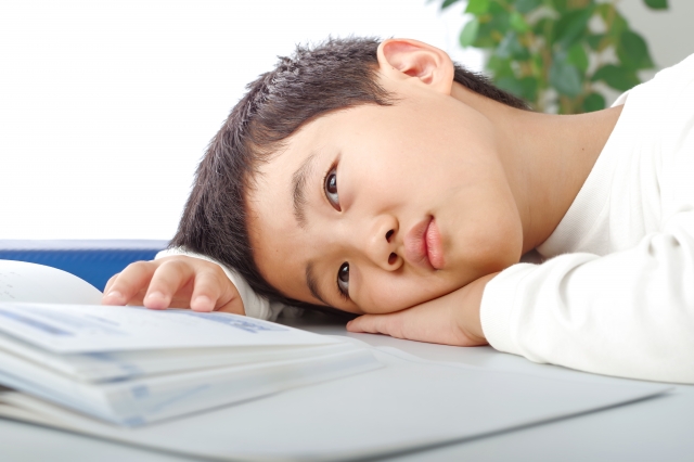 机に横になる男の子