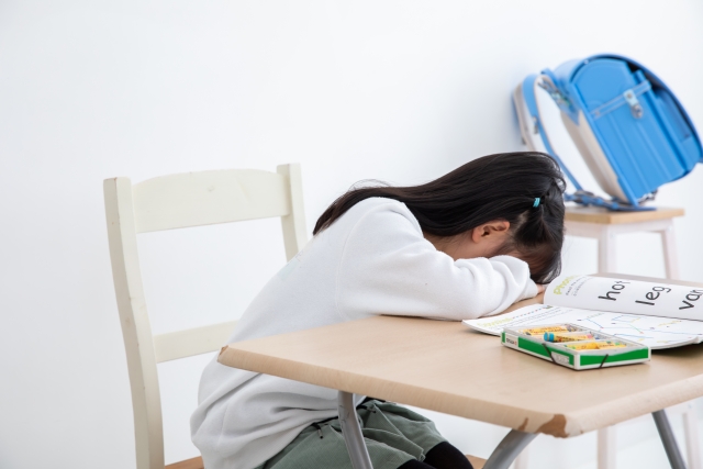 机に頭を伏せる女のこ