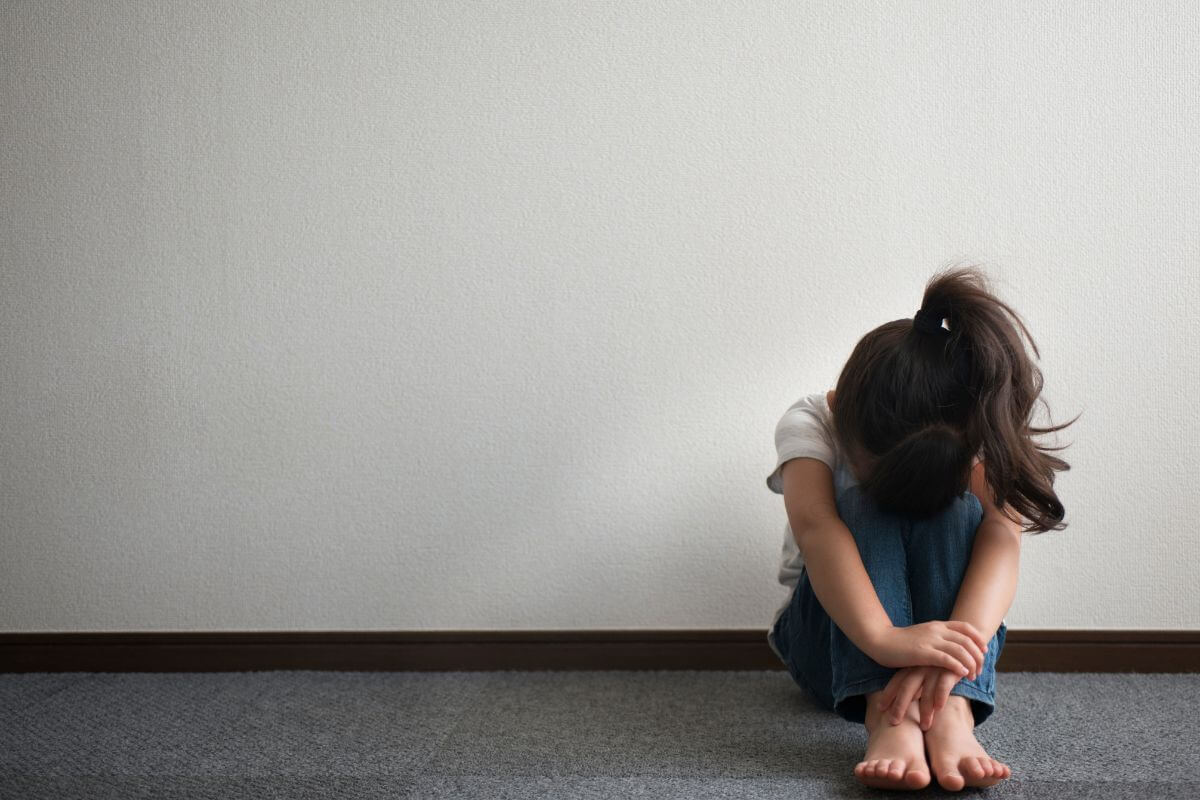 小さな女の子が座ってうつむいている様子。
