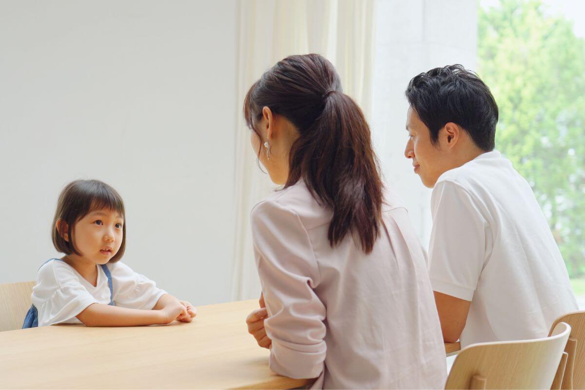 小さな女の子と保護者が向き合って話している様子。
